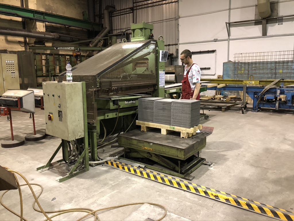 Stacked sheet cut-to-size pieces on the lift table behind the shear